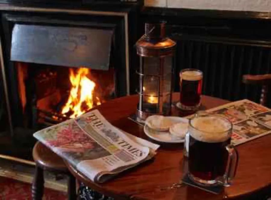 Dark ale and newspaper by a fireplace at the Crown and Trumpet