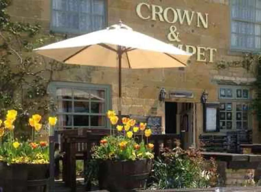 Outdoor tables and yellow flowers outside the Crown and Trumpet in Broadway