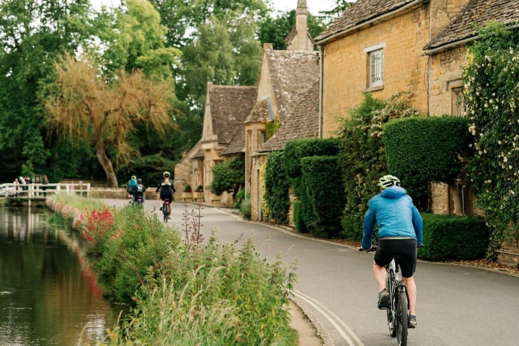 Cyclists riding through a Cotswold village