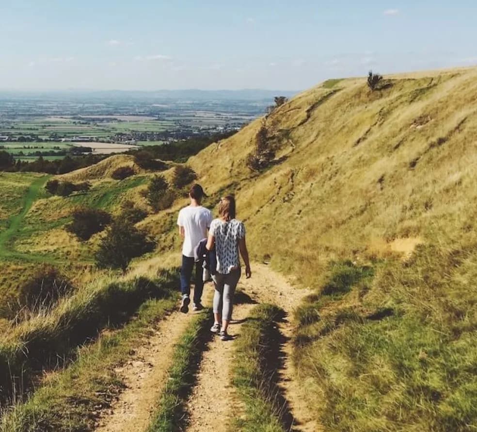 Two walkers on the Cotswold Way trail overlooking a valley