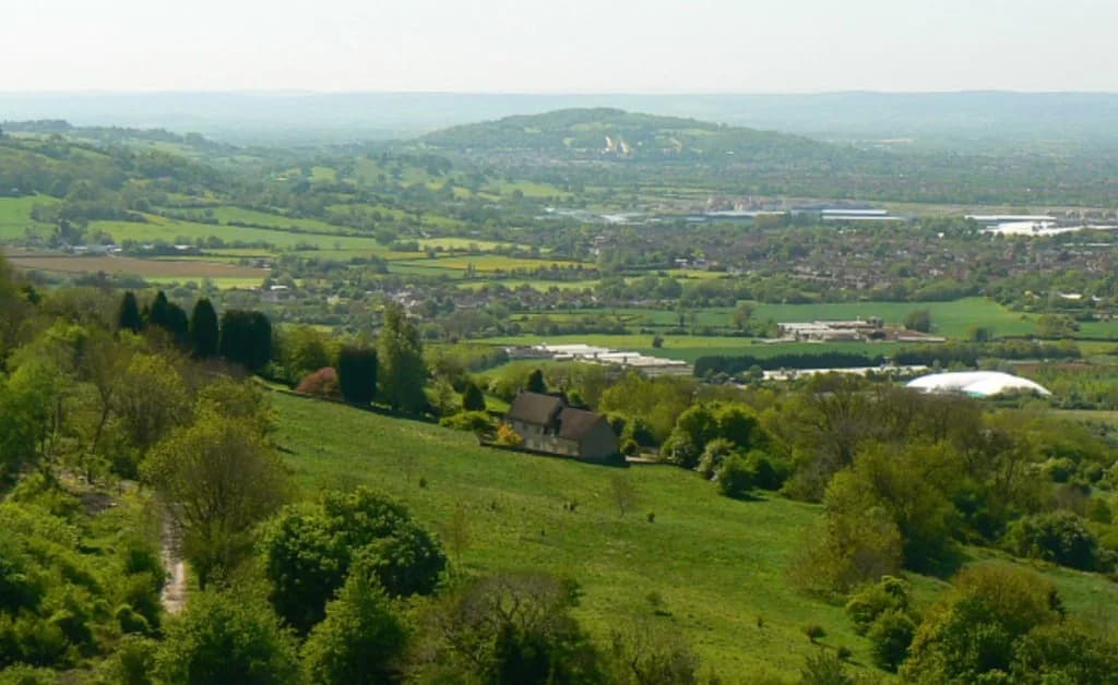 Panoramic view from Crickley Hill across the Severn Vale, with fields, hedgerows, and distant hills