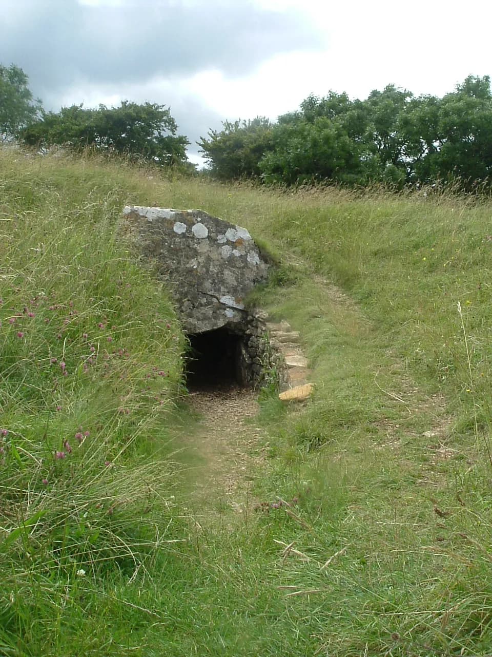 The grassed mound and stone entrance of Hetty Pegler's Tump (Uley Long Barrow) on the Cotswold escarpment