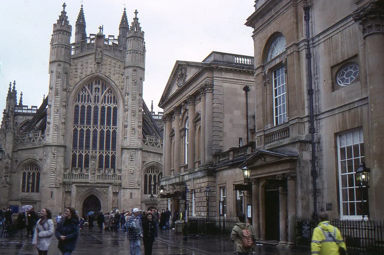 West front of Bath Abbey beside Georgian buildings on a wet day