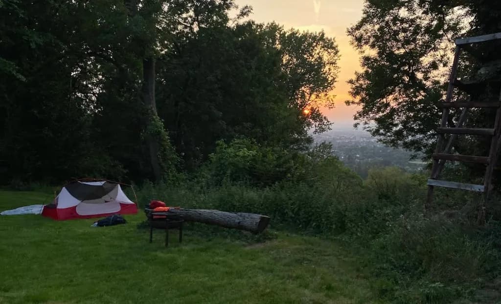 Tent pitched at Colgate Farm Campsite overlooking a valley at sunset