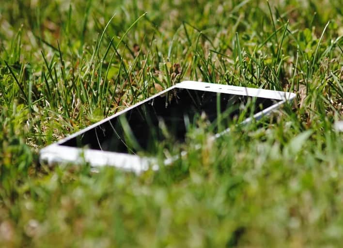 White smartphone lying in green grass outdoors