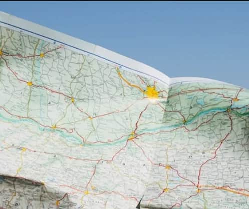 Folded paper roadmap held up against a clear blue sky