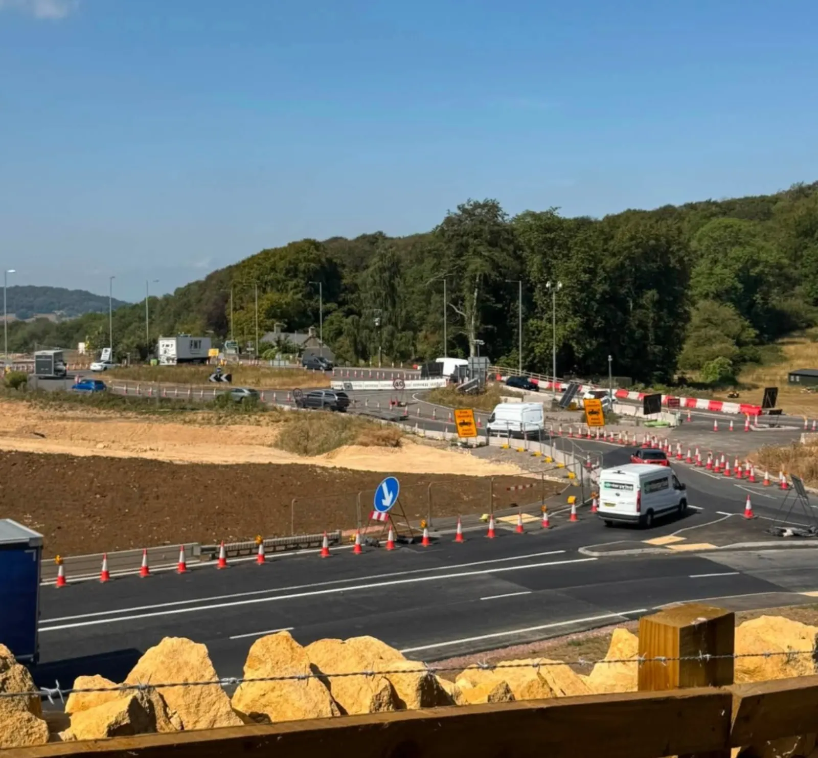 A417 Missing Link roadworks near Birdlip, with traffic cones, vans, and red-and-white fencing around the diverted carriageway